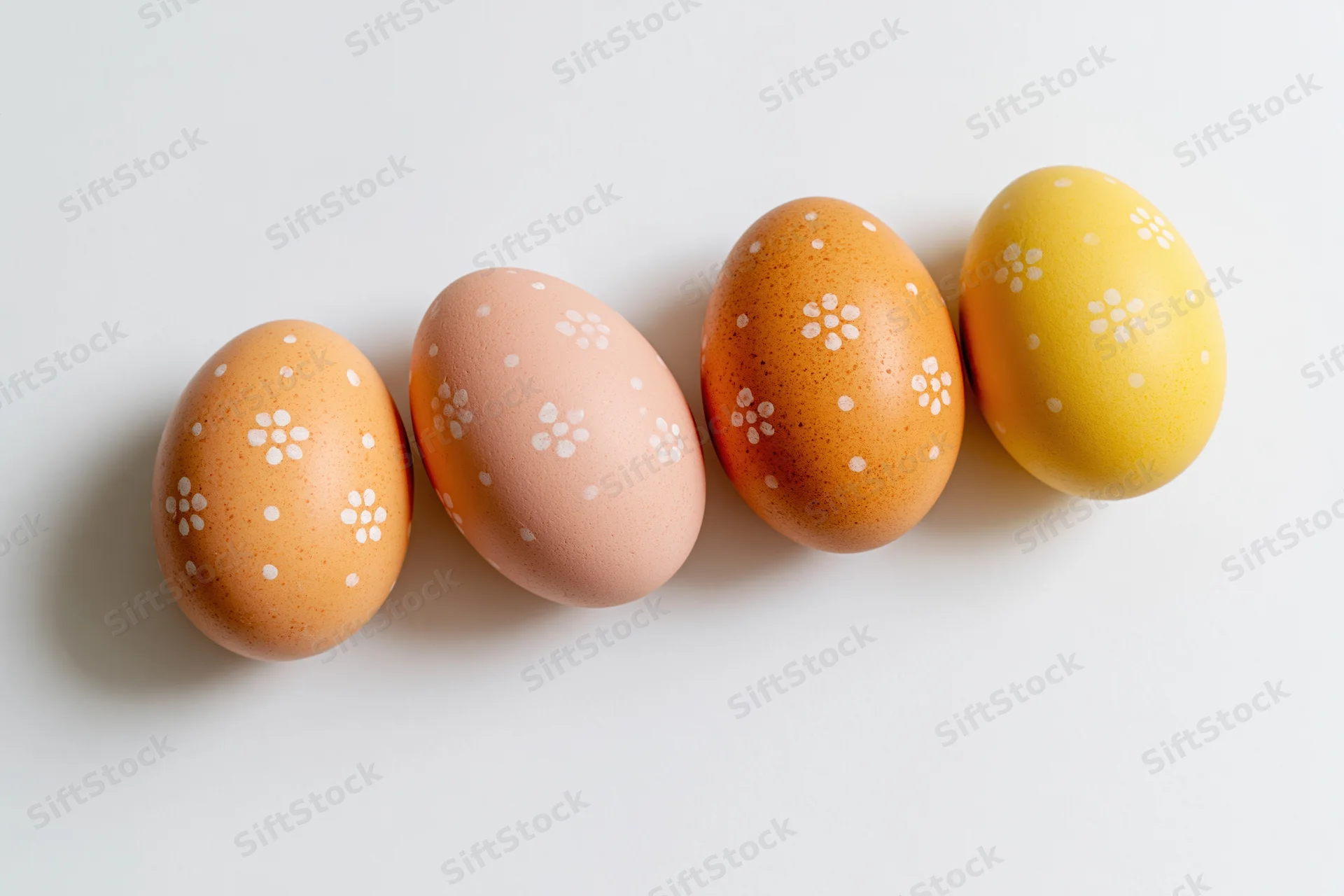 Four hand-painted easter eggs arranged in a horizontal row on a white surface