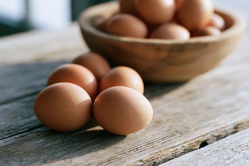 Brown chicken eggs arranged on a weathered wooden table