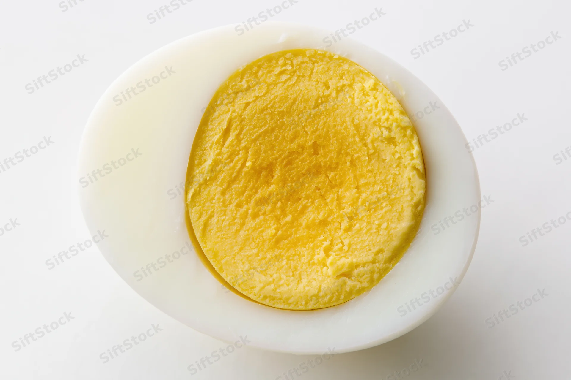 Half of a hard-boiled egg sliced lengthwise showing fully cooked yolk on white background