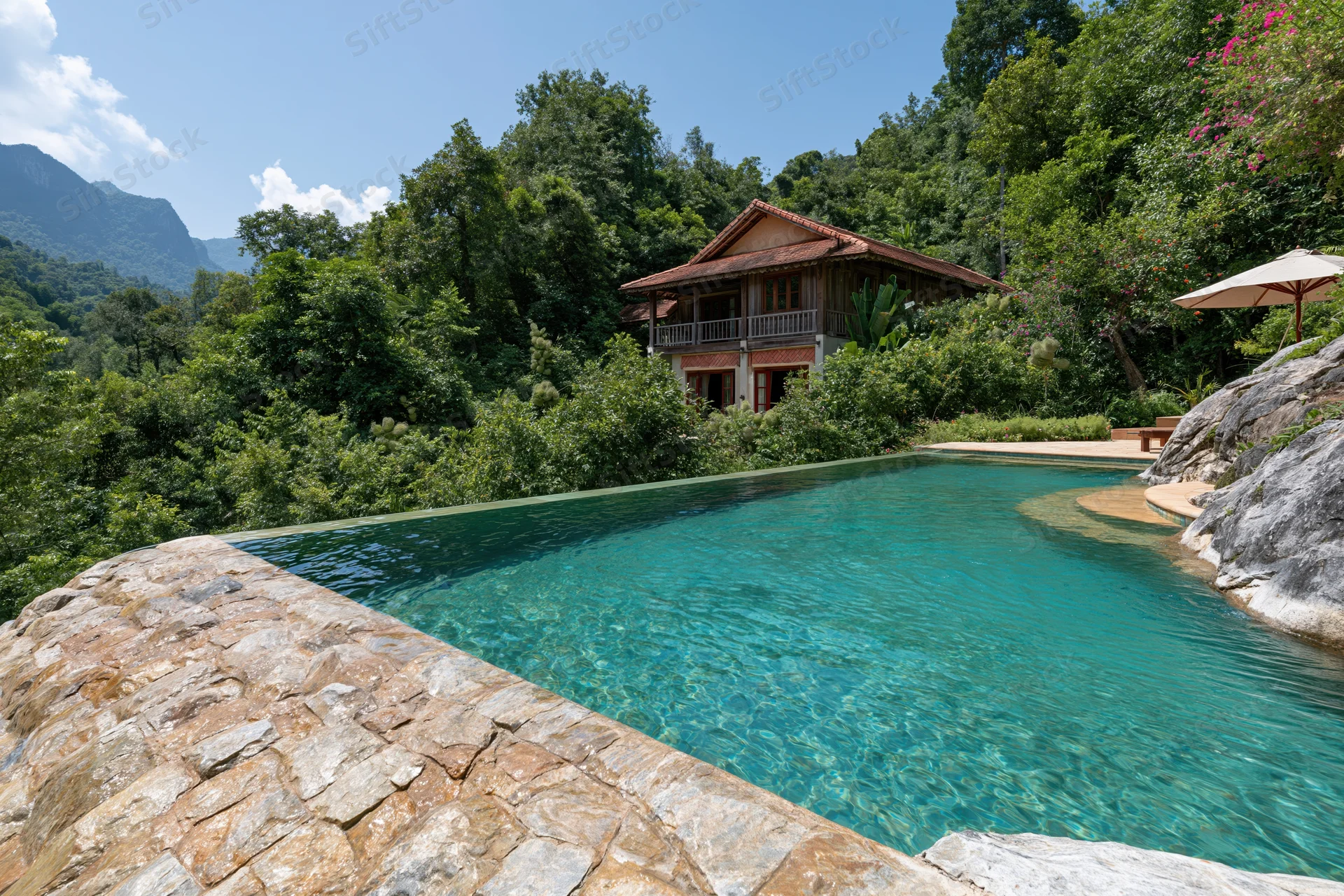 Infinity pool with turquoise water and natural stone edge surrounded by lush jungle and mountains