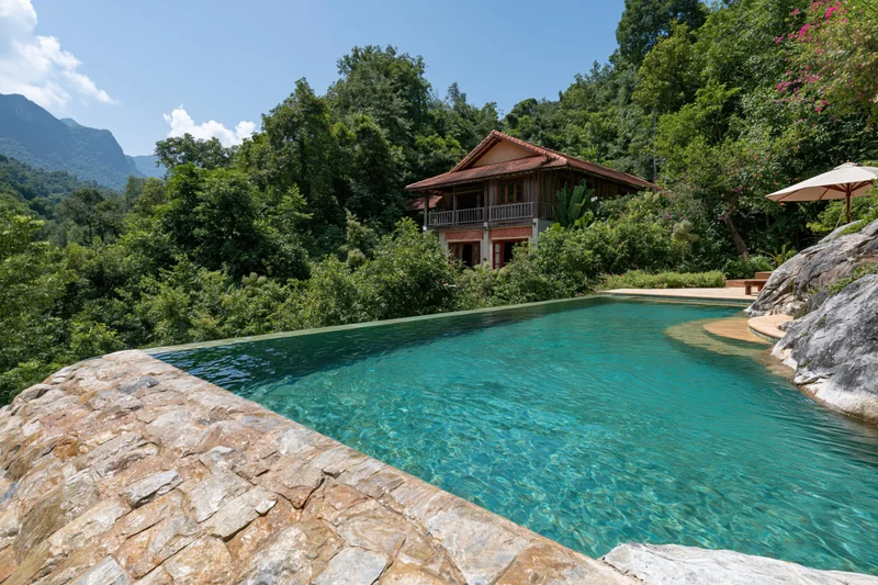 Infinity pool with turquoise water and natural stone edge surrounded by lush jungle and mountains