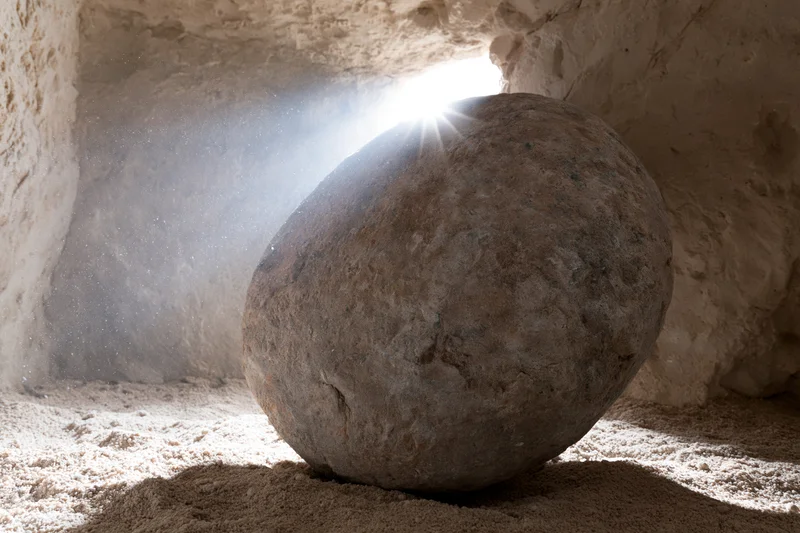 Large stone rolled aside from tomb entrance with sunlight streaming in