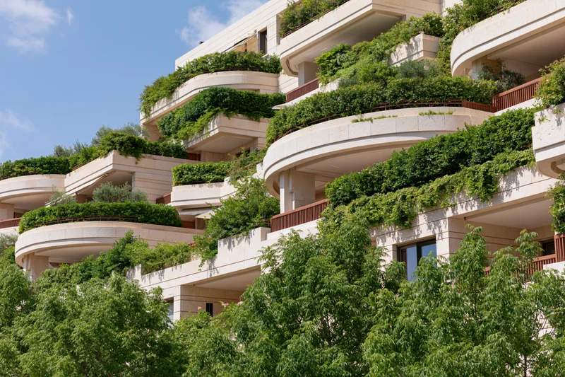 Luxury residential apartment building with curved balconies covered in green foliage and plants