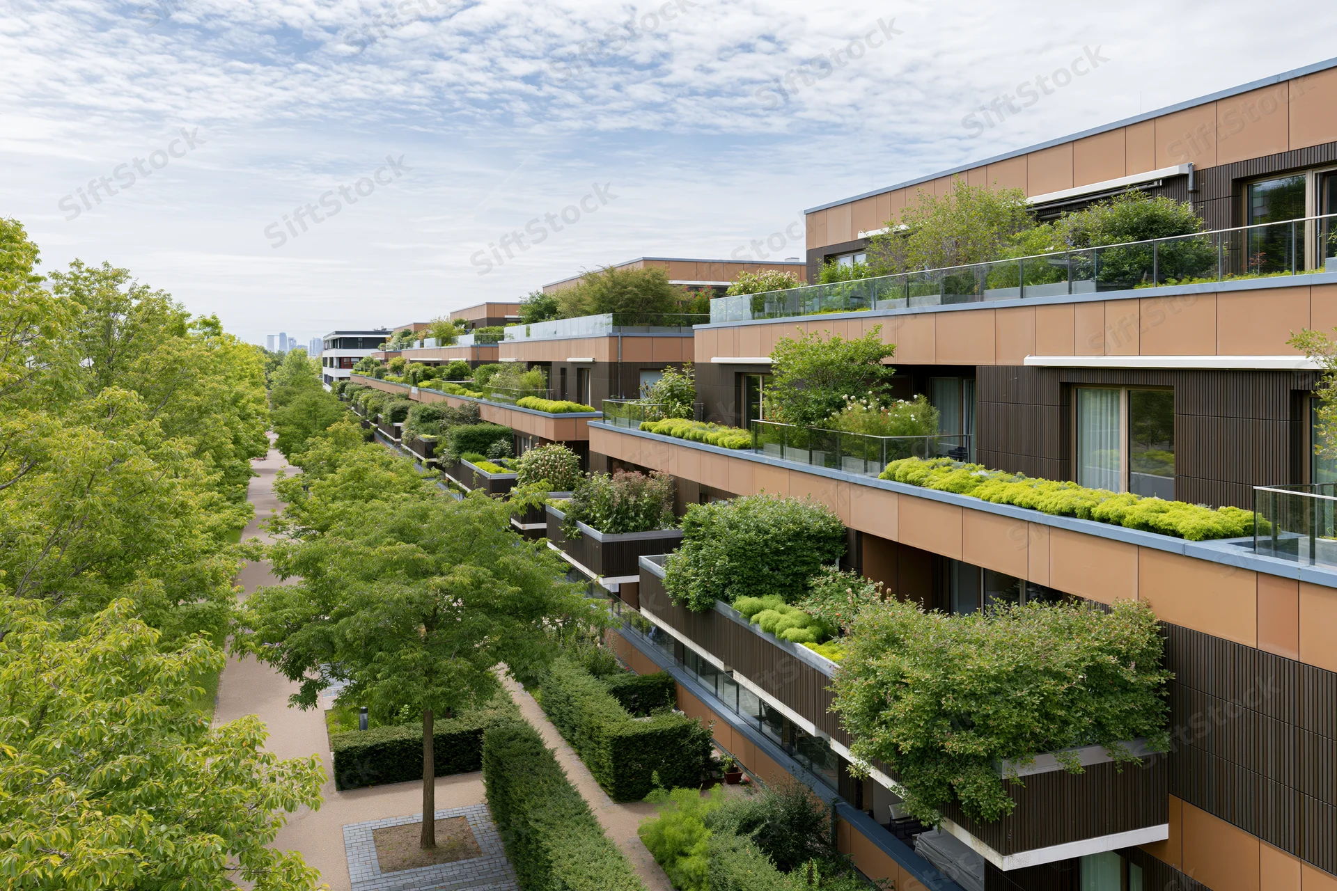 Modern residential apartment complex with rooftop gardens and balconies lined with greenery along a tree-lined walkway