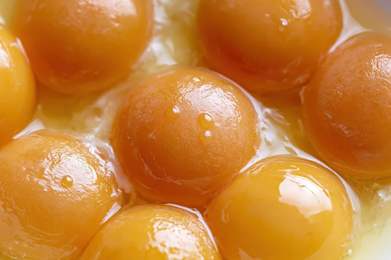 Multiple raw egg yolks clustered in a bowl viewed from above