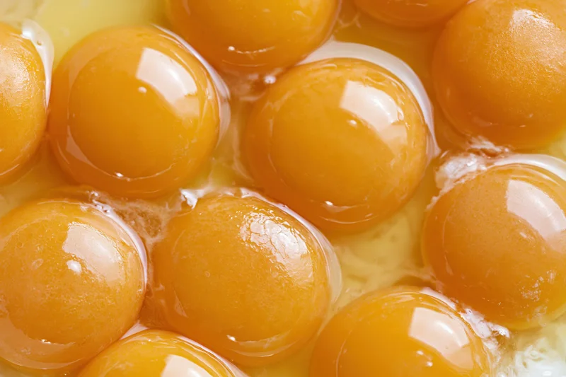 Multiple raw egg yolks in a bowl viewed from above
