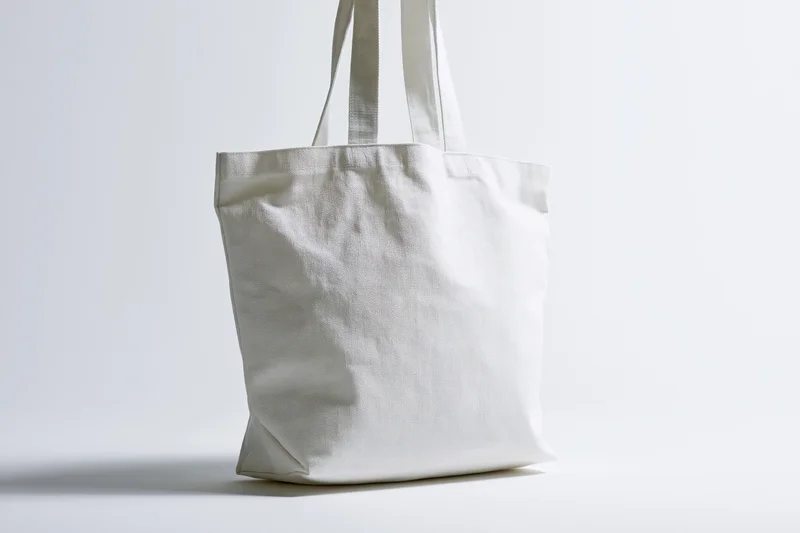 Plain white canvas tote bag standing upright centered against white background