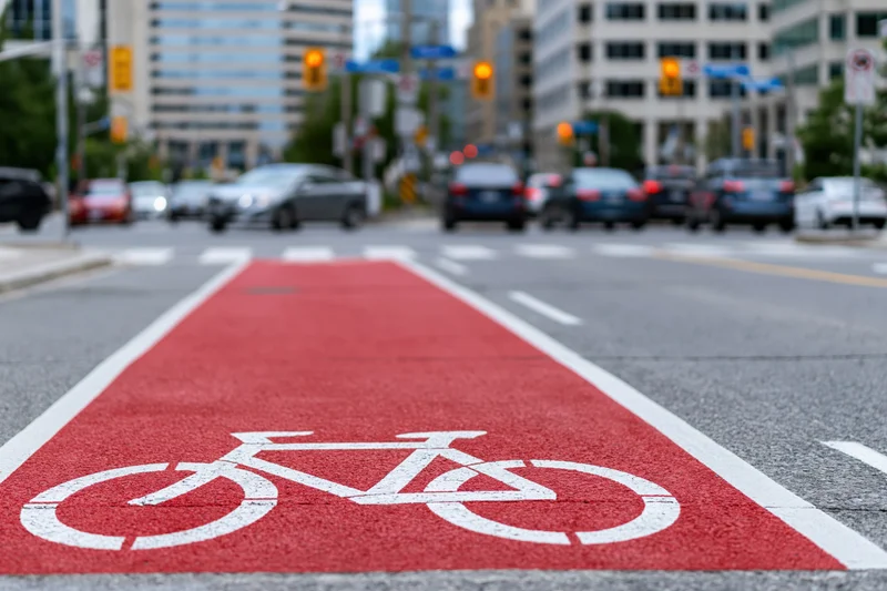 Red-painted bicycle lane with white cyclist symbol on urban street at intersection
