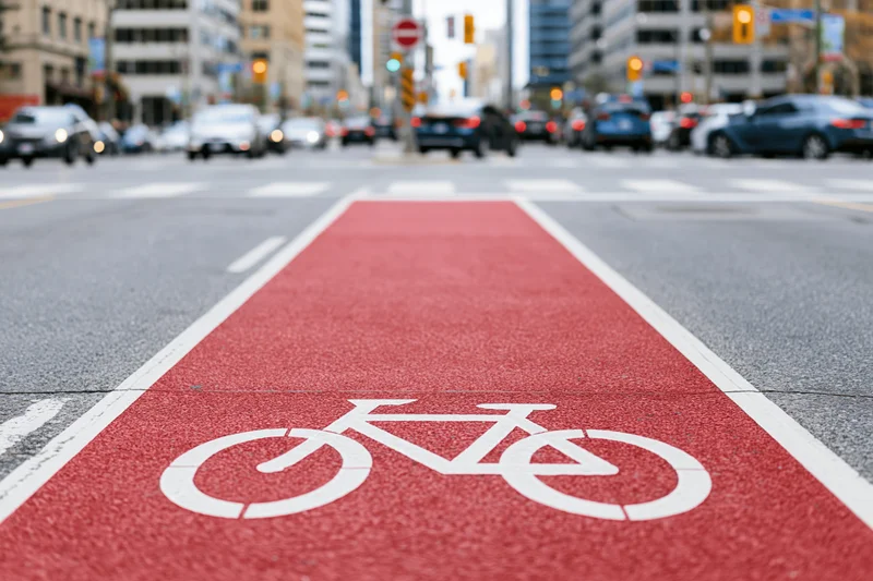 Red-painted bicycle lane with white cyclist symbol on urban street pavement