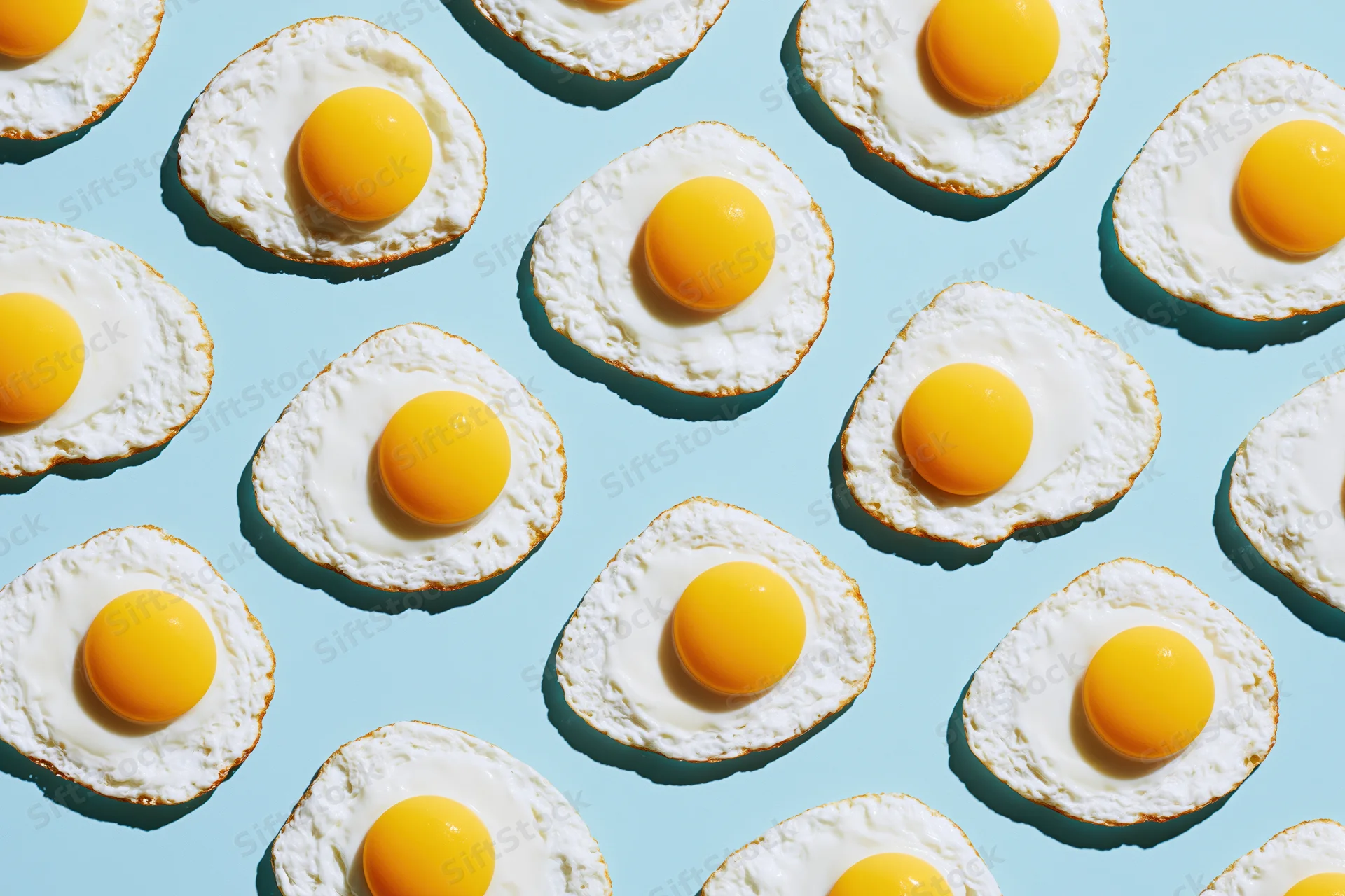 Fried eggs arranged in a repeating grid pattern on a blue background