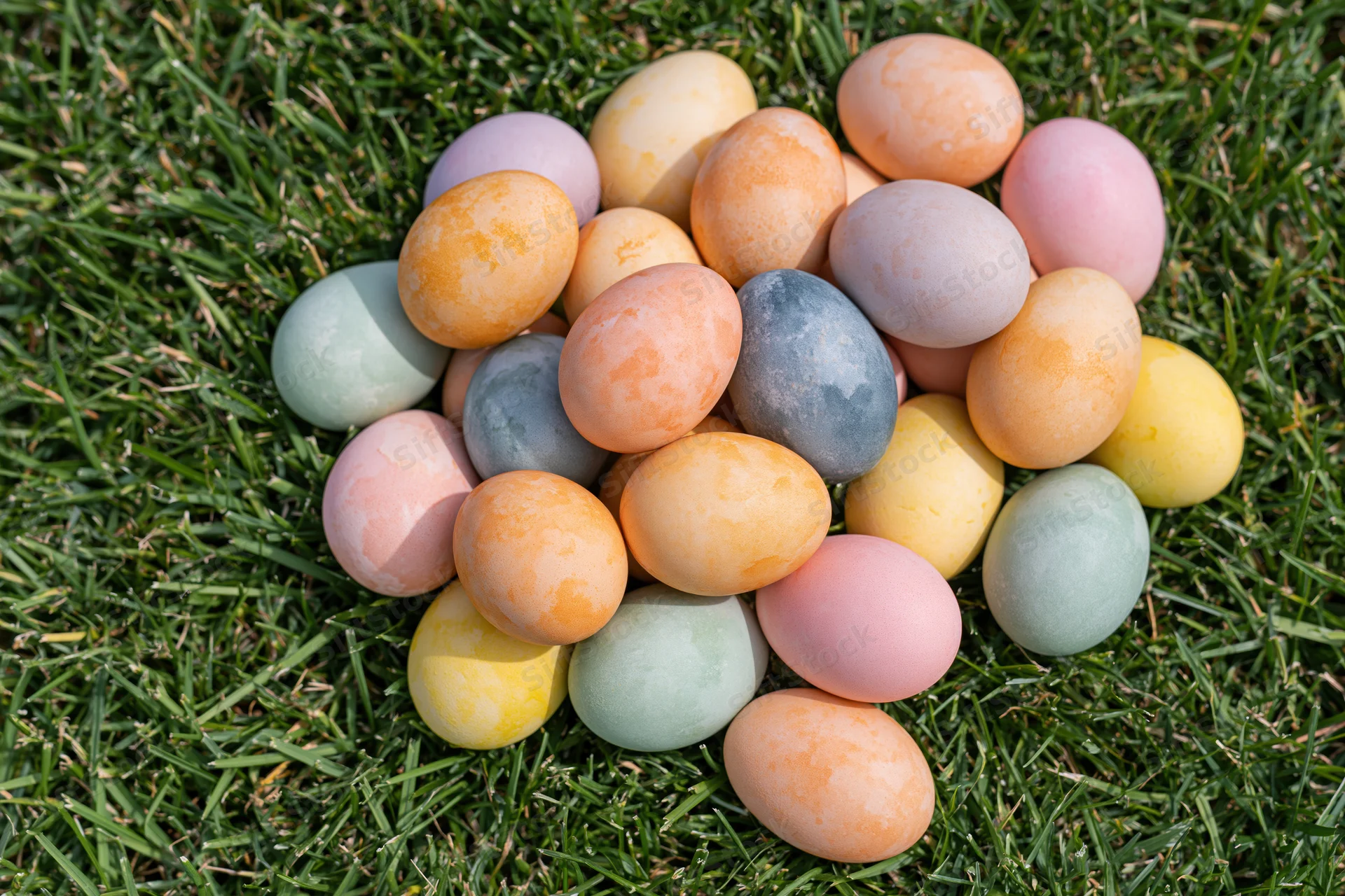 Hand-dyed easter eggs in pastel colors scattered on green grass