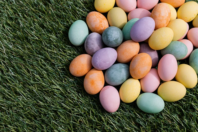 Hand-dyed easter eggs in pastel colors scattered on green grass