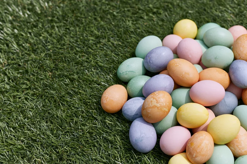 Hand-dyed easter eggs in pastel colors scattered on green grass in a garden setting