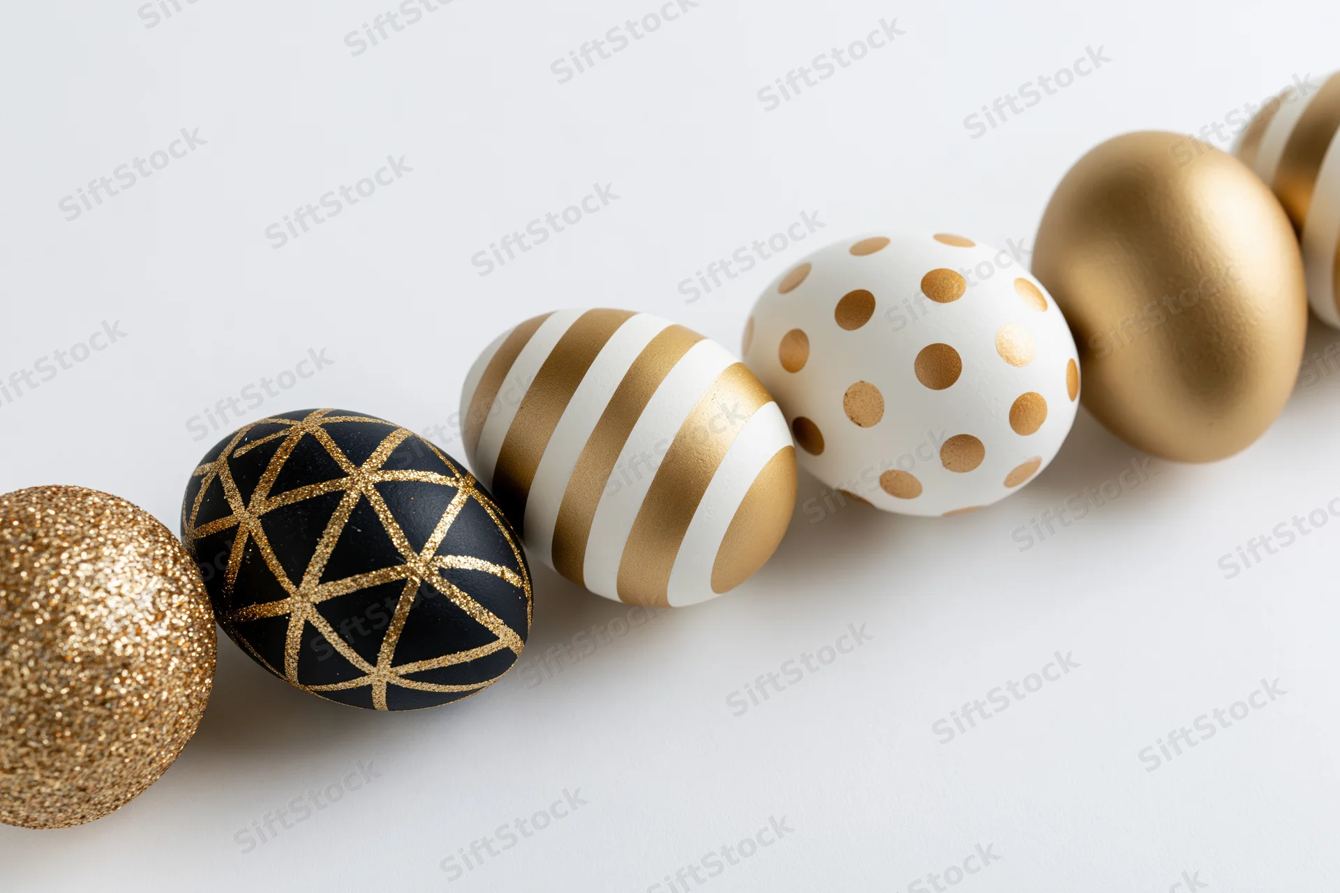 Seven decorated easter eggs arranged diagonally in a row on a white surface