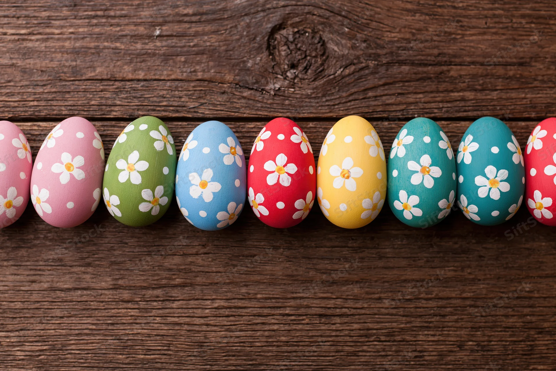 Hand-painted easter eggs with floral patterns arranged in a row on a wooden surface