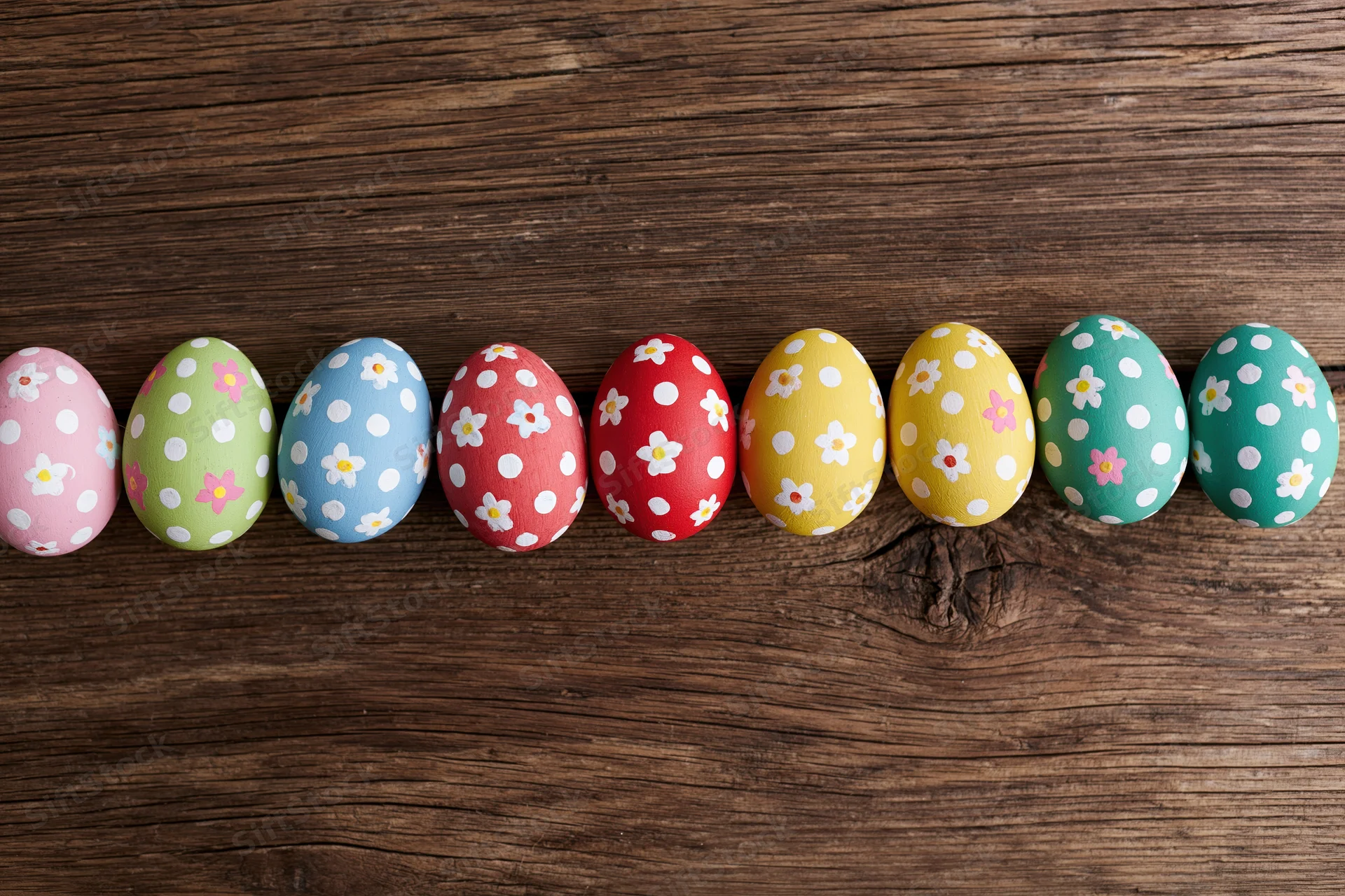 Hand-painted easter eggs arranged in a row on a wooden surface