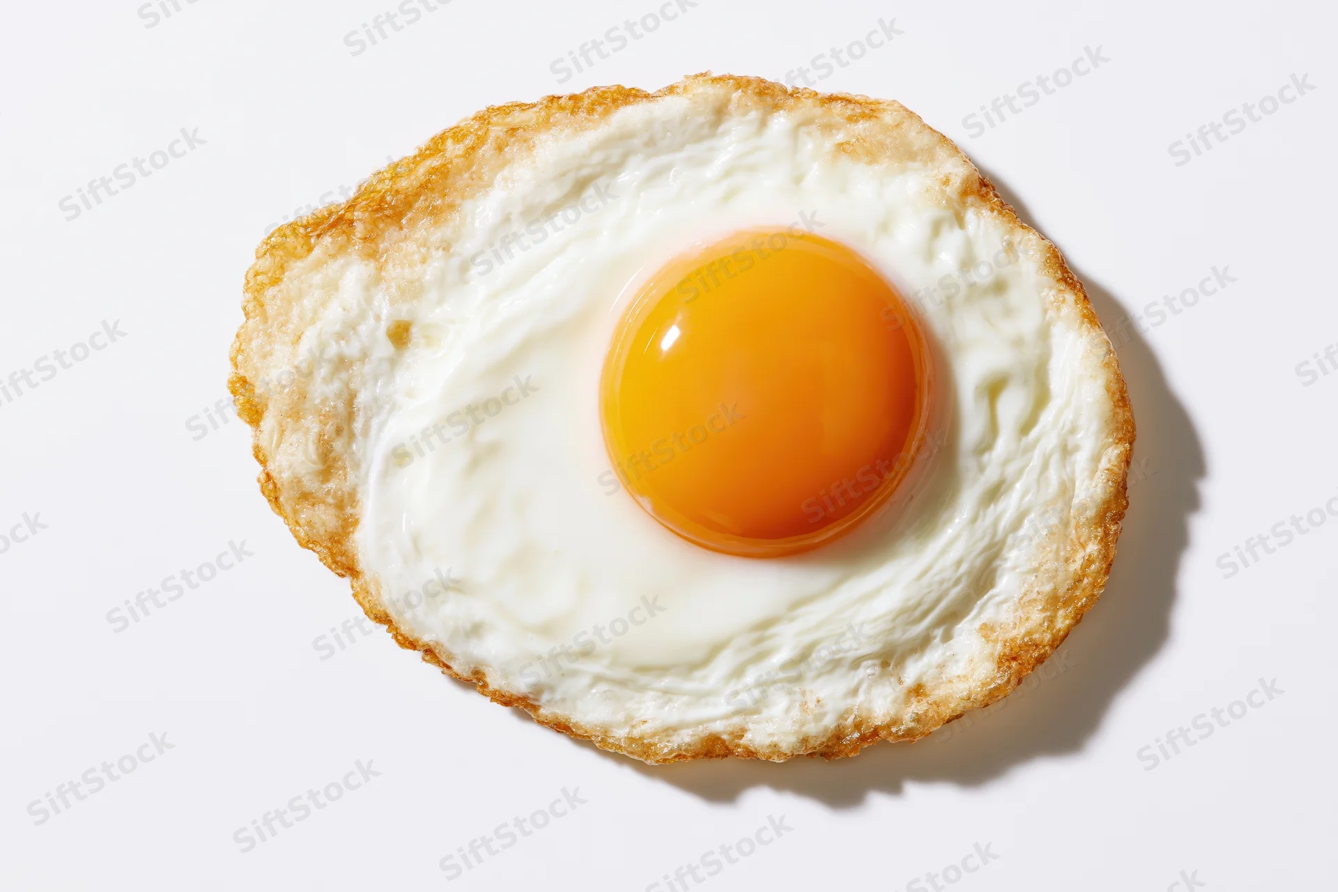 Single sunny-side-up fried egg viewed from directly overhead on white background