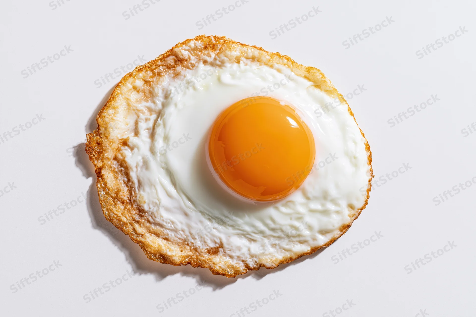 Single sunny-side-up fried egg viewed from directly overhead on white surface
