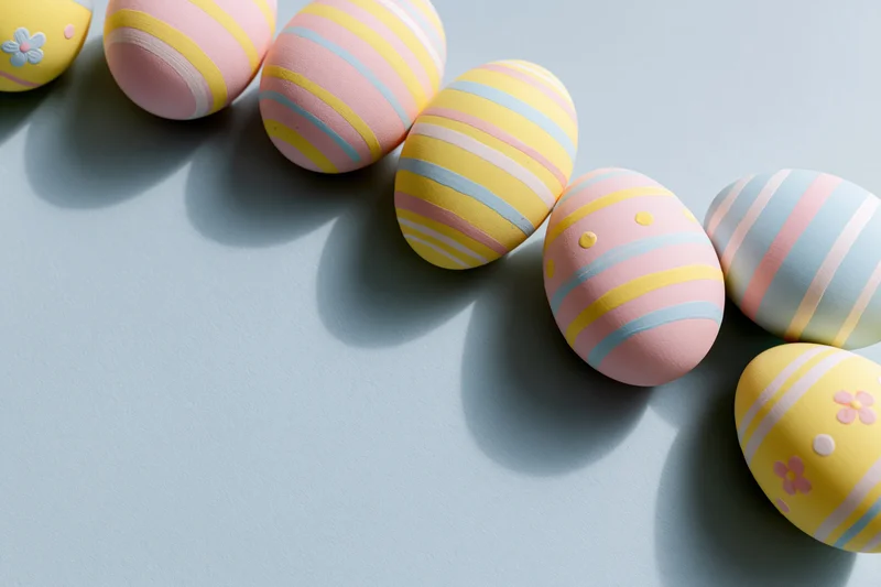 Decorated easter eggs arranged diagonally along the top and right edge on a light blue surface
