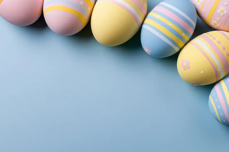Decorated easter eggs arranged along the top and right edge on a blue background with copyspace