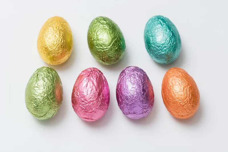 Foil-wrapped chocolate easter eggs arranged in two rows on white background