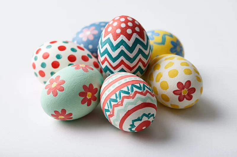 Hand-painted easter eggs arranged in a loose cluster on a white surface