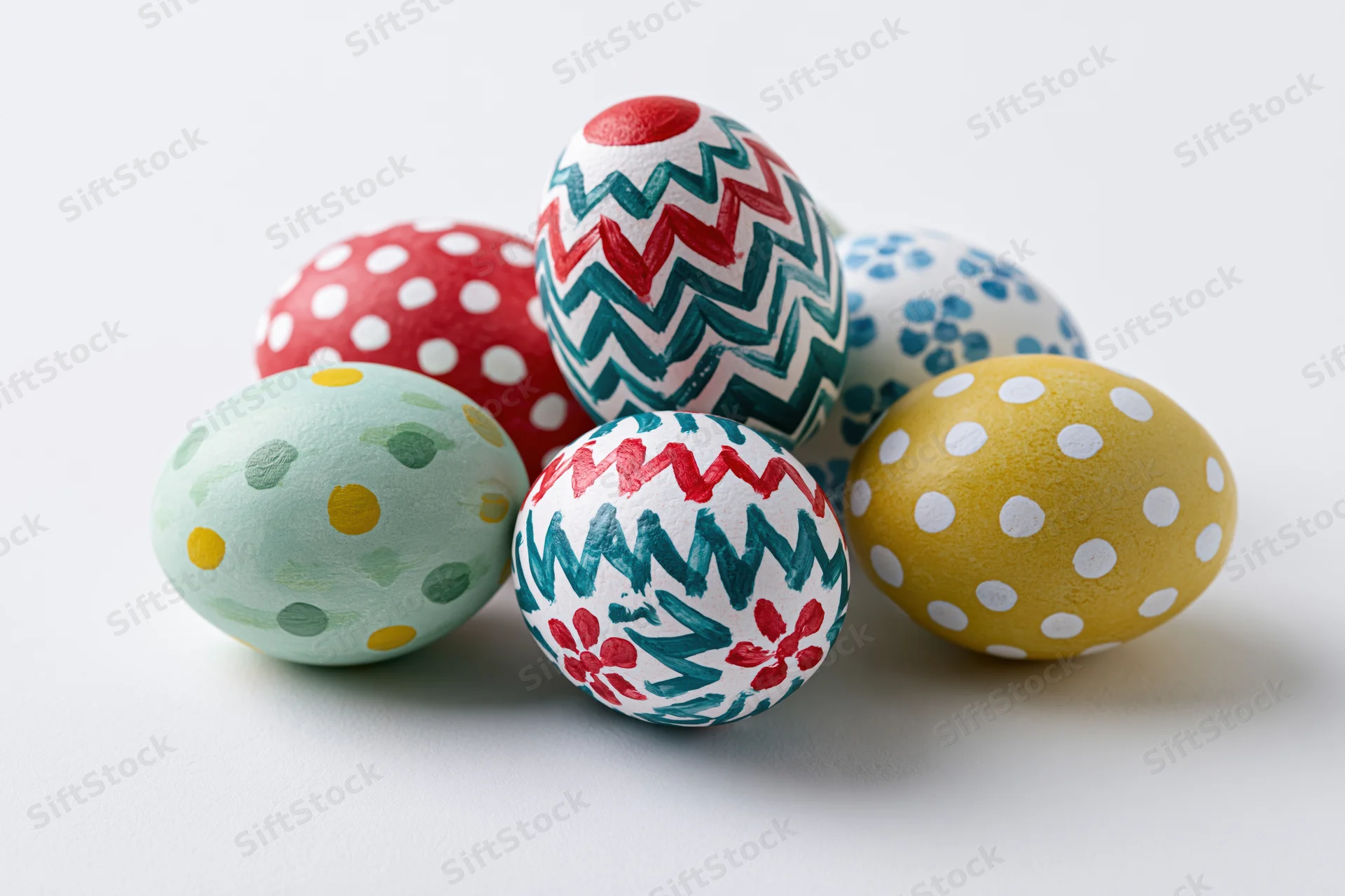Hand-painted easter eggs arranged in a loose cluster on a white surface