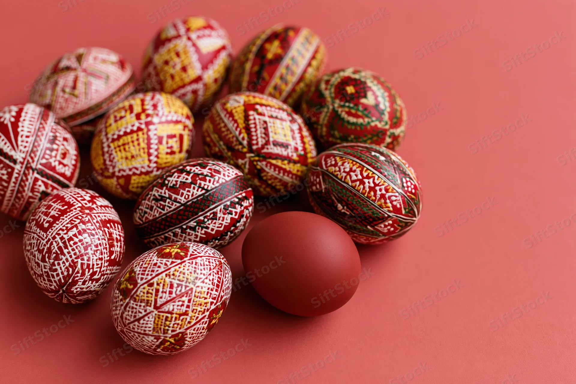 Traditional ukrainian pysanky easter eggs with intricate patterns arranged on a red surface