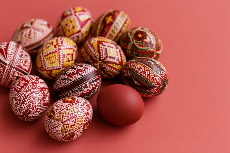 Traditional ukrainian pysanky easter eggs with intricate patterns arranged on a red surface