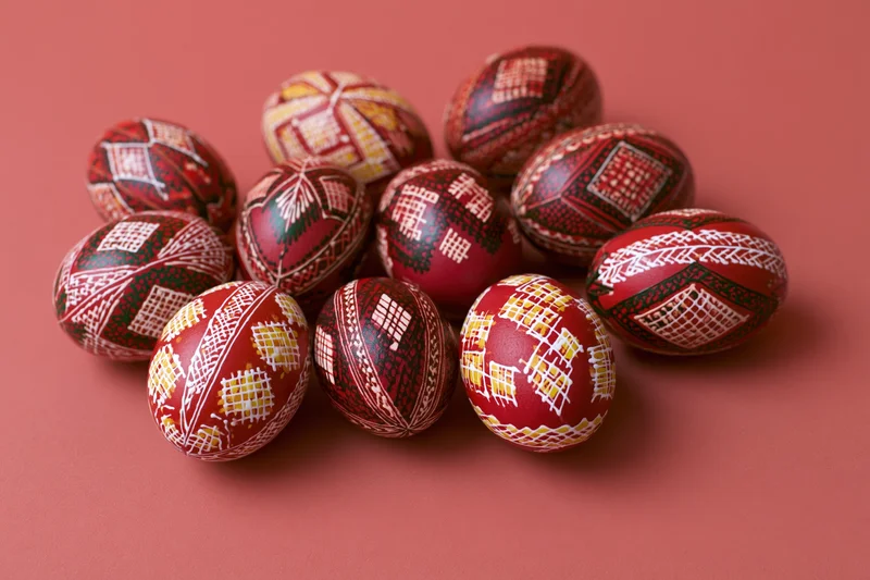 Ten traditional ukrainian pysanky easter eggs with intricate patterns arranged on a red background