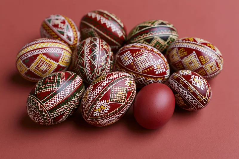 Traditional ukrainian pysanky easter eggs with intricate patterns arranged in a cluster on a red surface