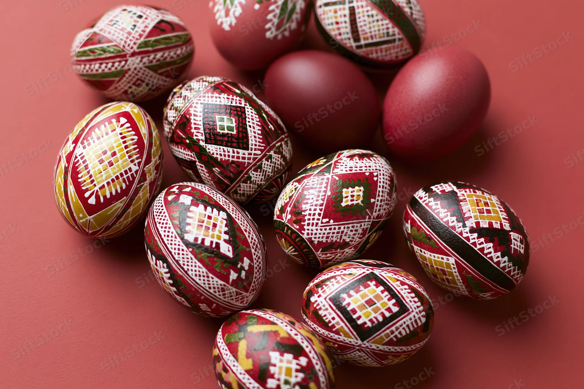 Traditional ukrainian pysanky easter eggs with intricate geometric patterns arranged on a red surface
