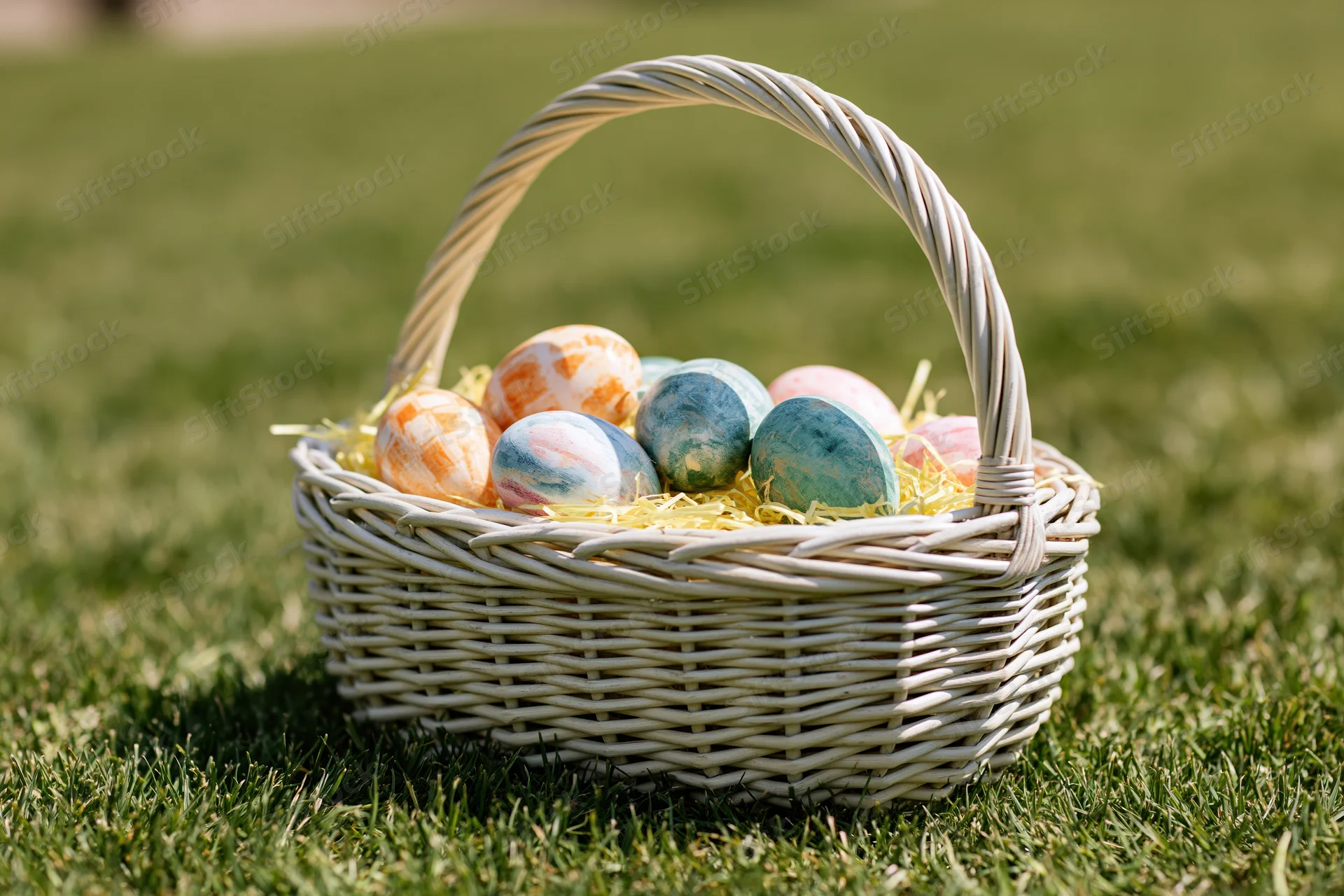 Wicker basket filled with hand-painted easter eggs on green grass