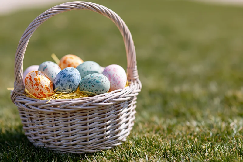 Wicker basket filled with hand-painted easter eggs on green grass