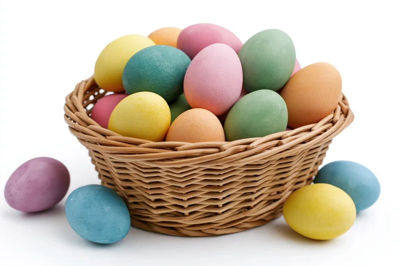 Woven wicker basket filled with dyed easter eggs in pastel colors on white background