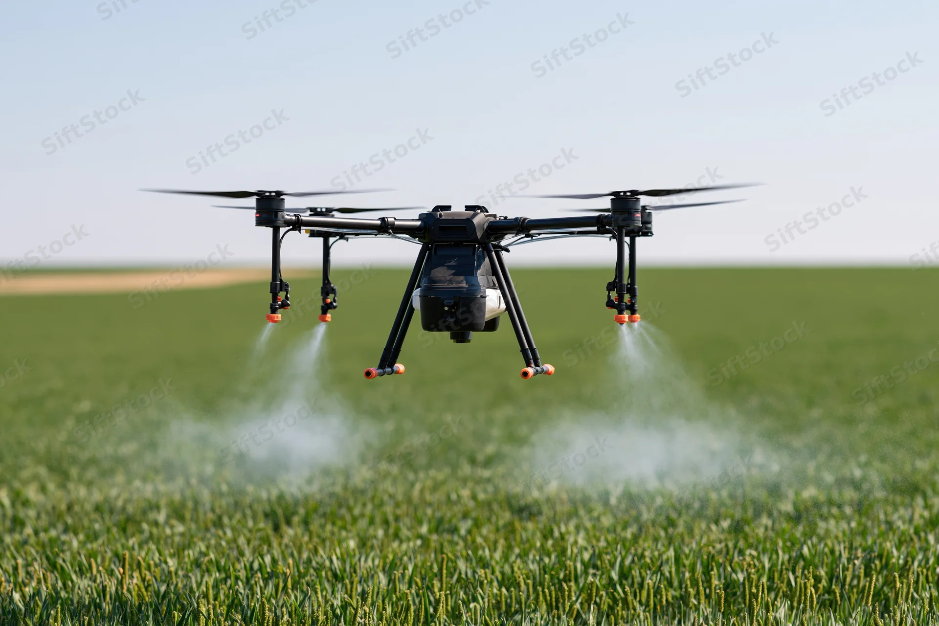Agricultural drone spraying liquid mist over a green crop field
