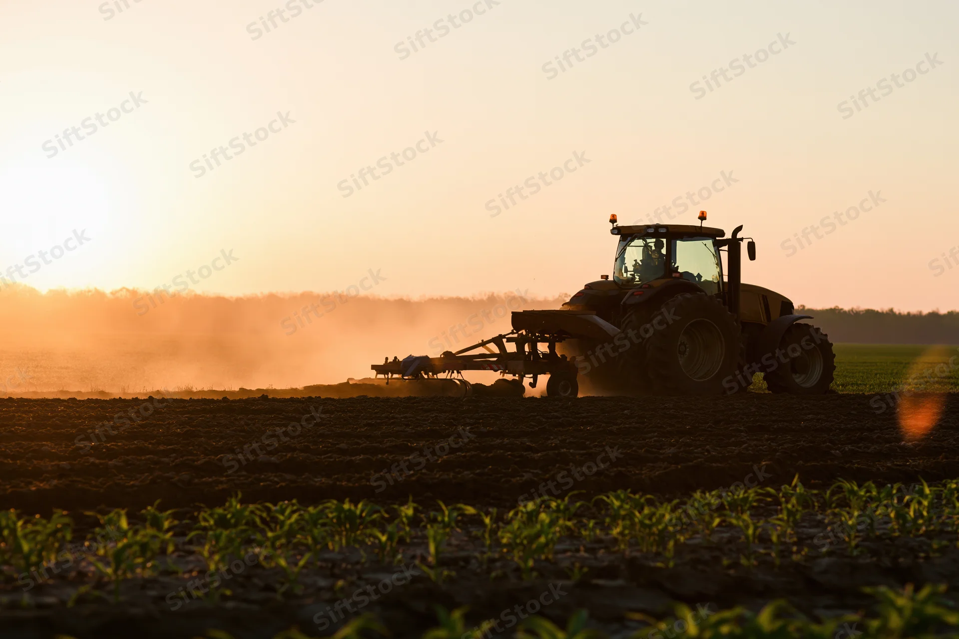 Large farm tractor pulling a plow across a flat field