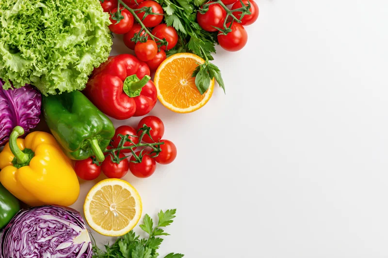 Fresh vegetables and fruits arranged loosely in the corner on white background with copyspace