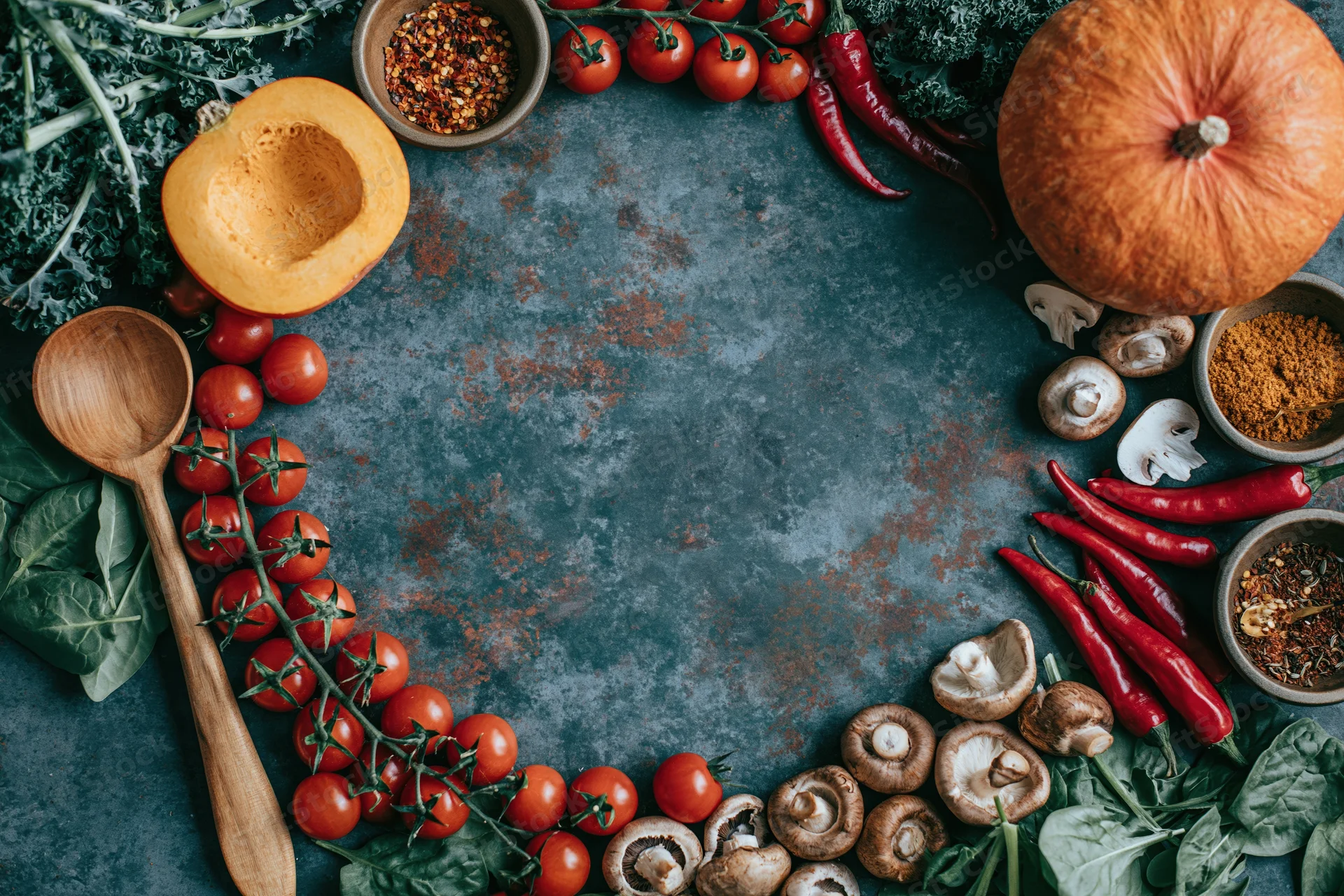 Autumn vegetables and cooking tools arranged in a flat lay frame on a dark textured surface with copyspace