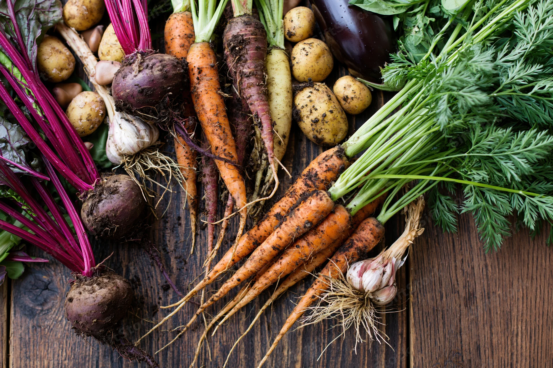 Freshly harvested vegetables arranged loosely on a dark wooden table
