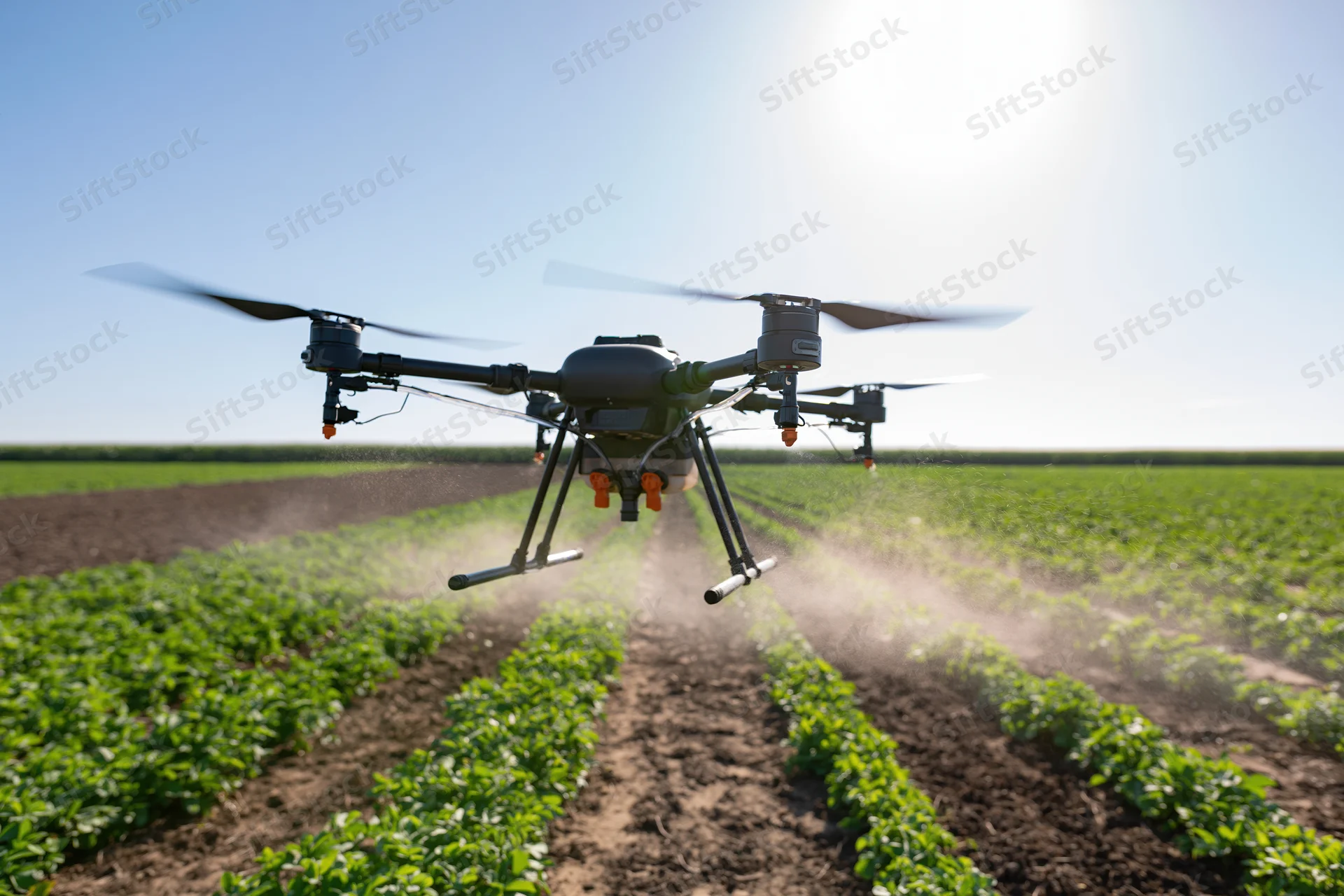 Agricultural sprayer drone hovering low over rows of crops in a field