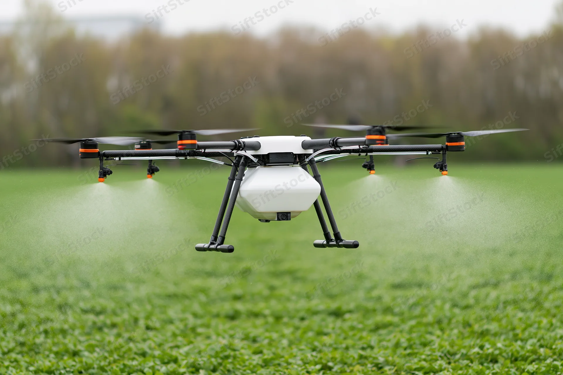 Agricultural sprayer drone hovering low over a green crop field spraying mist