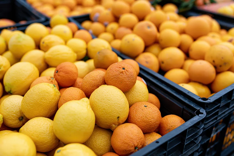 Lemons and mandarins piled in black crates at an outdoor market stall