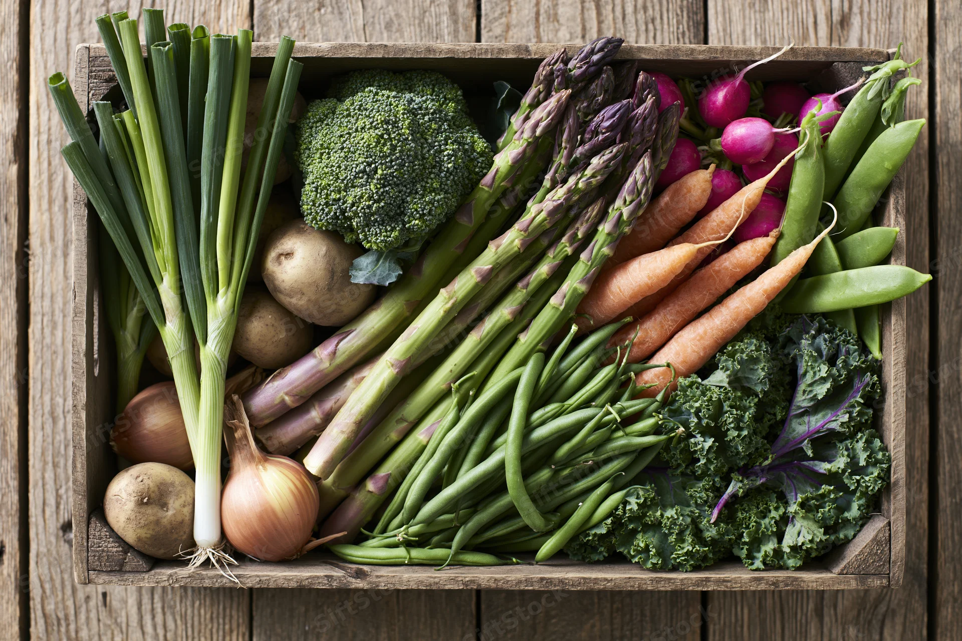 Wooden crate filled with fresh vegetables arranged in flat lay on rustic surface