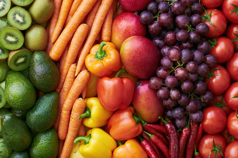 Overhead flat lay of densely packed fresh fruits and vegetables arranged in vibrant colors and textures