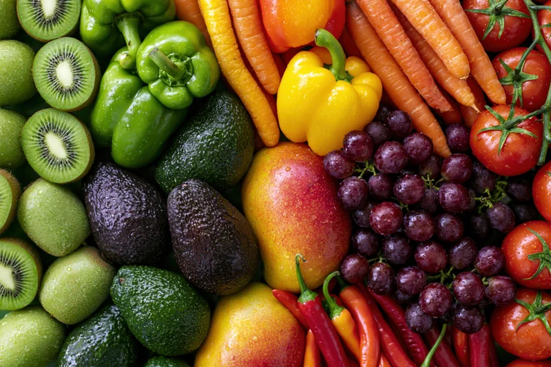 Overhead flat lay of densely packed fresh fruits and vegetables arranged on a white surface