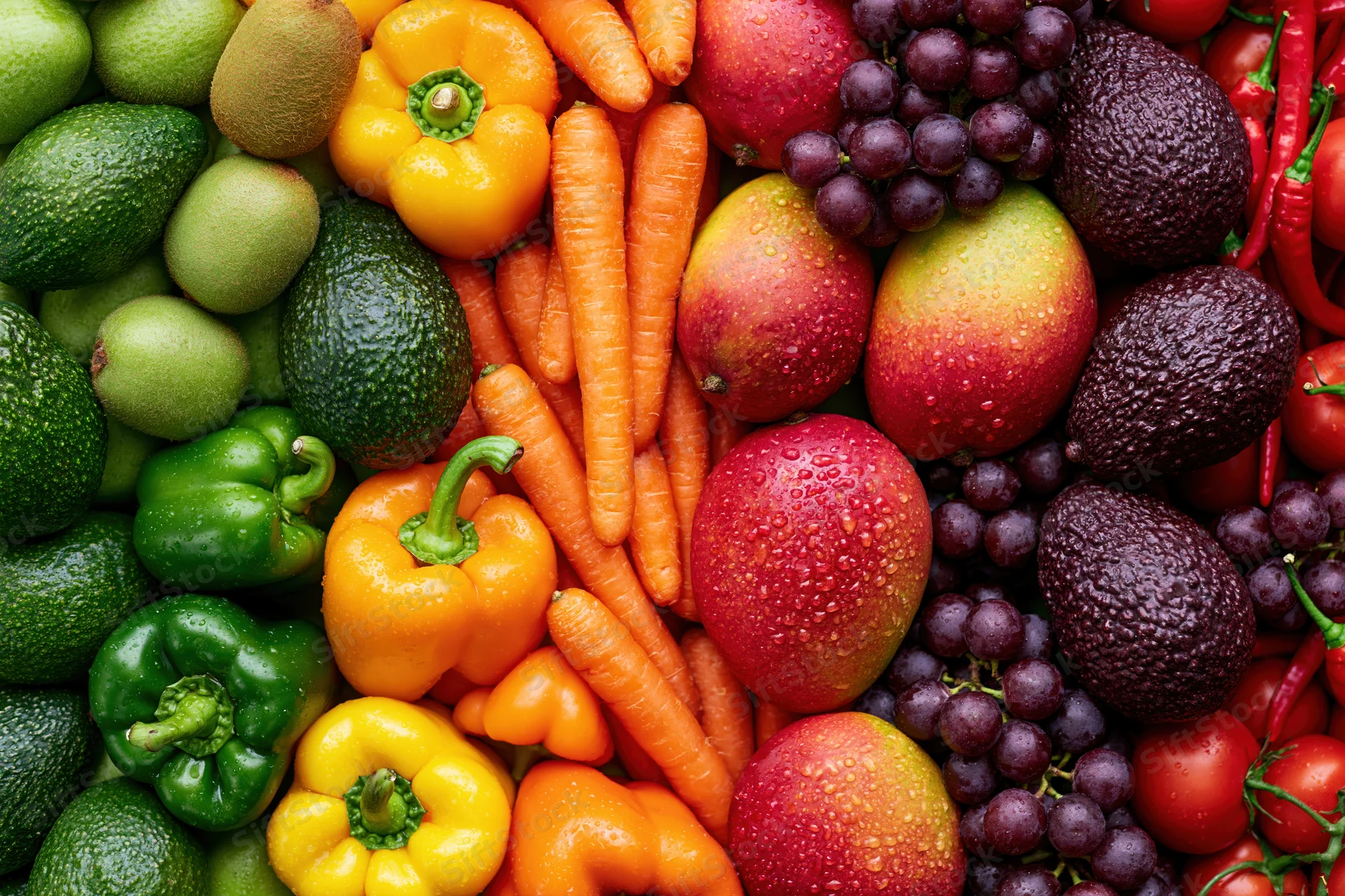 Overhead flat lay of densely packed fresh fruits and vegetables with water droplets on a flat surface