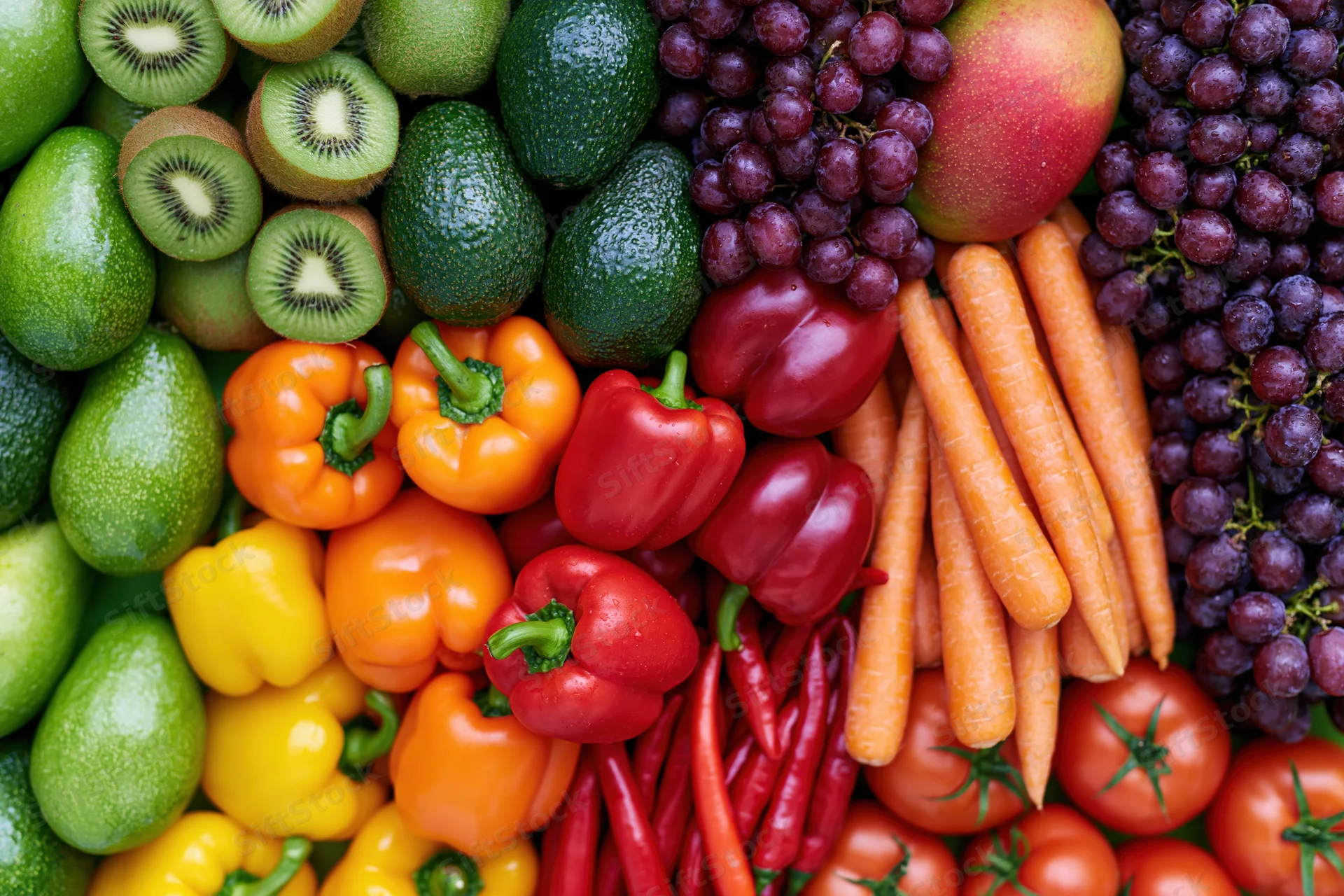 Overhead flat lay of densely packed fresh fruits and vegetables arranged in a colorful pattern on a flat surface