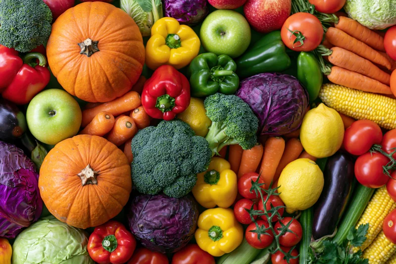 Overhead flat lay of densely packed fresh vegetables and fruits in a colorful arrangement
