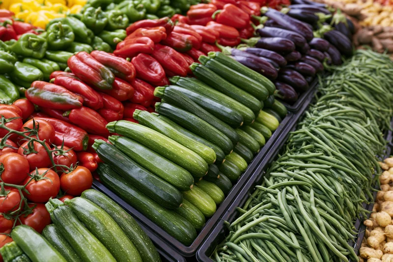 Overhead view of fresh vegetables arranged in rows at an outdoor market stall